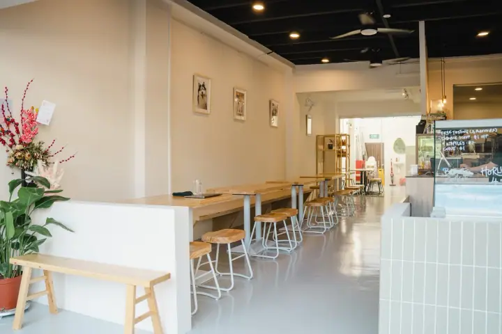 A dog resting on the pavement outside On Pause cafe on Lowland Road, Singapore, with the small specialty coffee bar's open frontage and a barista preparing a V60 visible inside.